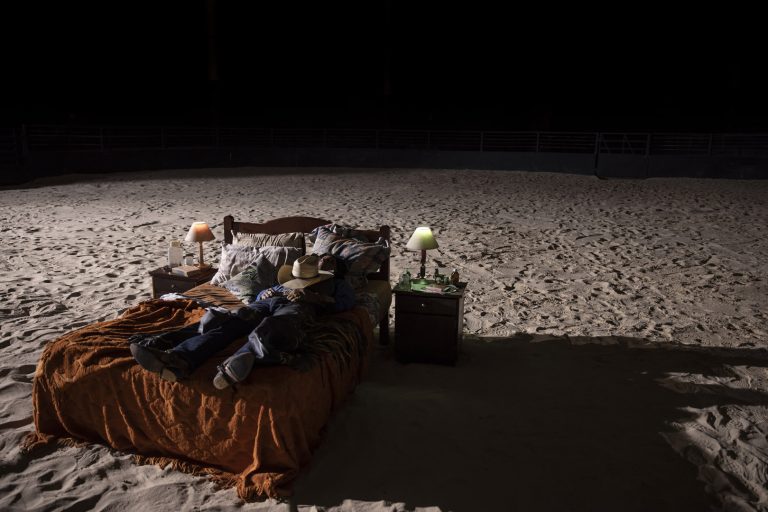FERNANDOPOLIS, SP, BRASIL, 27-04-2024: Asa Branca acorda na arena, em sua cama.      . Asa Branca queria ser peão, mas um acidente de montaria pôs fim a esse sonho. Durante a recuperação, o único jeito de se manter próximo à arena era ouvir as locuções do dia do seu acidente e de outras narrações clássicas. De tanto ouvir, Asa começa a brincar de fazer rimas até que tem a sua primeira oportunidade de narrar, ao cobrir a falta de um locutor numa noite de rodeio. A proximidade com a arena e a chance de fazer com que o público sinta a emoção da montaria mudam a vida de Asa, tanto que ele abre mão do amor da sua vida, para seguir carreira como locutor de rodeio.Mas Asa Branca não é um locutor qualquer, ele quer cada vez mais emoção. Para isso, ele precisa enfrentar toda a tradição dos rodeios no início dos anos 90, representada pela figura do empresário Jotapê e toda a influência que ele exerce no interior de São Paulo. Munido pelo desejo de inovar, e cercado por um time implacável com sua DJ, os peões e políticos influentes, Asa se lança numa jornada sem volta em busca da máxima adrenalina nas arenas. Microfone sem fio, rock pesado, fogos de artifício e até a chegada triunfante em um helicóptero são marcas deixadas por Asa nas montarias pelo interior do país. Contra ele, toda a tradição das Festas do Peão. A seu favor, as arenas cheias e a certeza que depois de AsaBranca os rodeios nunca mais seriam os mesmos. (Foto: Fabio Braga/Pivô Audiovisual) DIVULGAÇÃO.
